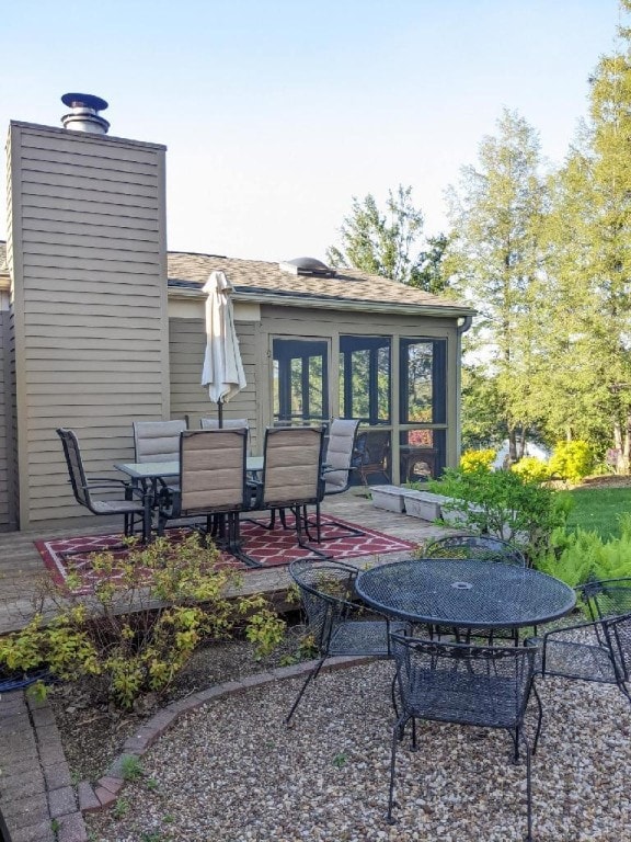back of property with outdoor dining area, a chimney, and a patio