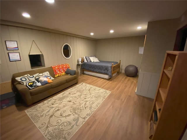 bedroom featuring wood finished floors, a decorative wall, and recessed lighting