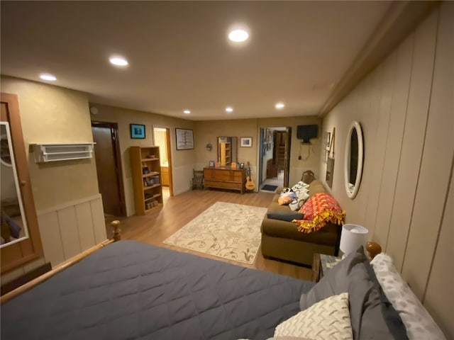 bedroom featuring wood finished floors, recessed lighting, and a decorative wall
