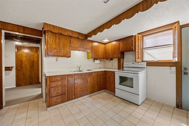 kitchen with a sink, a textured ceiling, brown cabinets, light countertops, and electric stove
