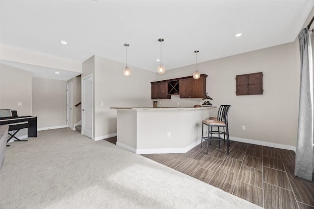 919 Camp Cardinal Rd, Iowa City, IA 52246 - kitchen featuring baseboards, dark brown cabinetry, pendant lighting, and a breakfast bar area