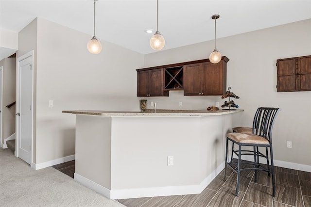 919 Camp Cardinal Rd, Iowa City, IA 52246 - kitchen with light countertops, dark brown cabinets, baseboards, hanging light fixtures, and a breakfast bar area