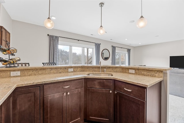 919 Camp Cardinal Rd, Iowa City, IA 52246 - kitchen with a sink, dark brown cabinets, open floor plan, pendant lighting, and light stone counters