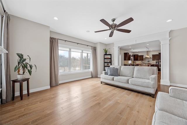 919 Camp Cardinal Rd, Iowa City, IA 52246 - living room featuring light wood-type flooring, a ceiling fan, baseboards, and ornate columns