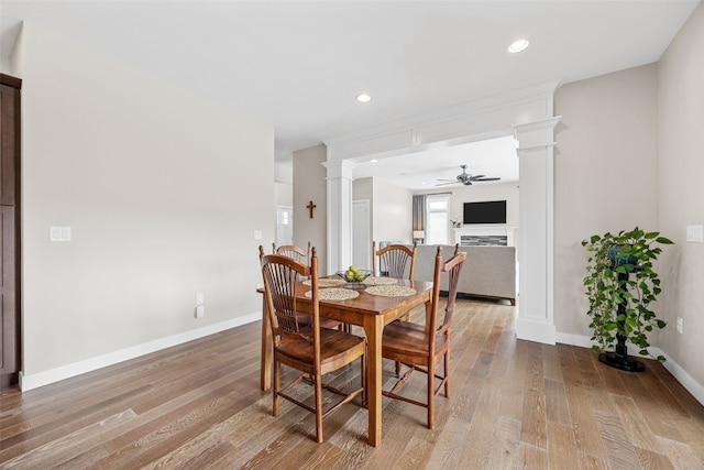919 Camp Cardinal Rd, Iowa City, IA 52246 - dining room featuring wood finished floors, ceiling fan, a fireplace, baseboards, and ornate columns