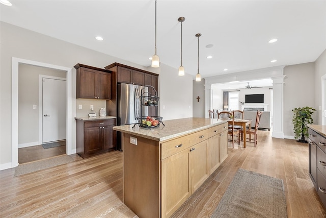 919 Camp Cardinal Rd, Iowa City, IA 52246 - kitchen with a center island, light wood-style flooring, freestanding refrigerator, and ornate columns