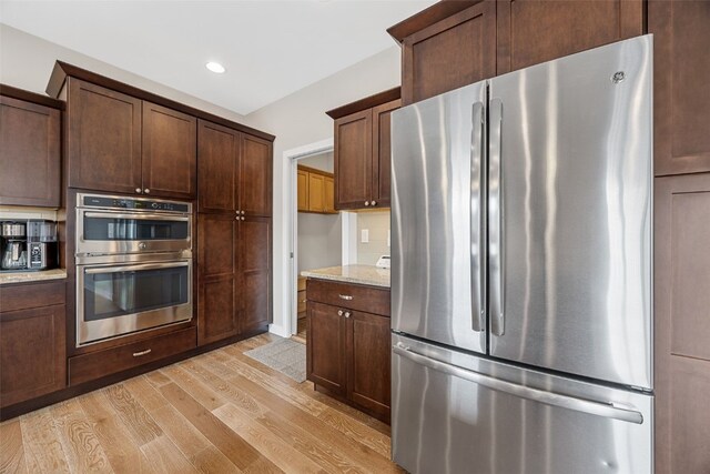 919 Camp Cardinal Rd, Iowa City, IA 52246 - kitchen with light stone counters, dark brown cabinets, light wood-style floors, stainless steel appliances, and recessed lighting