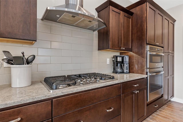 919 Camp Cardinal Rd, Iowa City, IA 52246 - kitchen featuring backsplash, wall chimney exhaust hood, dark brown cabinetry, and stainless steel appliances