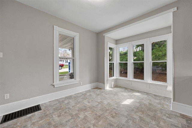 unfurnished room featuring baseboards and stone finish floors