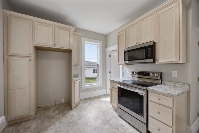 kitchen featuring appliances with stainless steel finishes, light brown cabinets, and baseboards