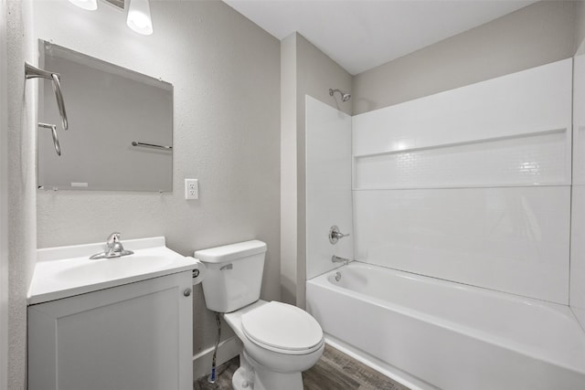 full bathroom with wood finished floors, toilet, vanity, shower / tub combination, and a textured wall