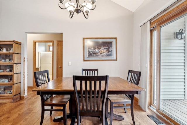 dining space with a chandelier, light wood-style flooring, and lofted ceiling