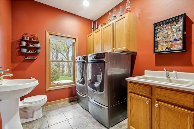 laundry area featuring independent washer and dryer, light tile patterned flooring, and baseboards