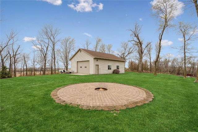 view of green lawn with an outdoor structure, a detached garage, and a fire pit