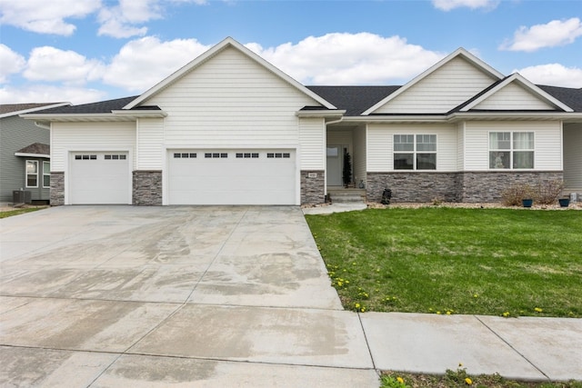 933 Commercial St, Lisbon, IA 52253 - view of front of house featuring an attached garage, stone siding, driveway, a front lawn, and central AC unit