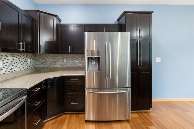 kitchen with light wood finished floors, stainless steel appliances, light stone countertops, and tasteful backsplash