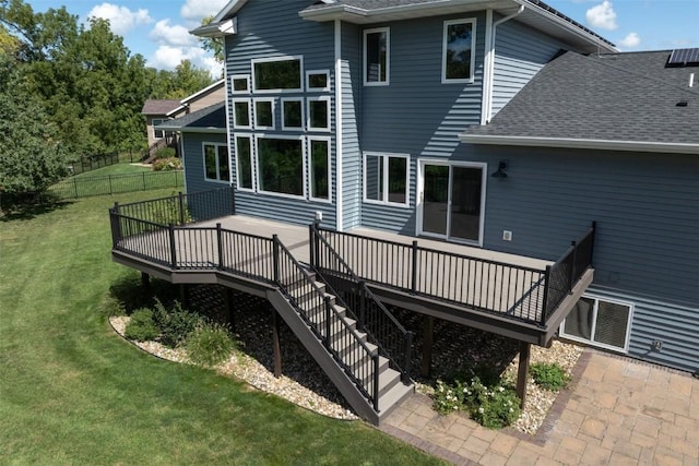 back of property with fence, a wooden deck, a lawn, a shingled roof, and stairs