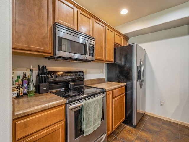 kitchen featuring stainless steel appliances, light countertops, recessed lighting, and brown cabinets