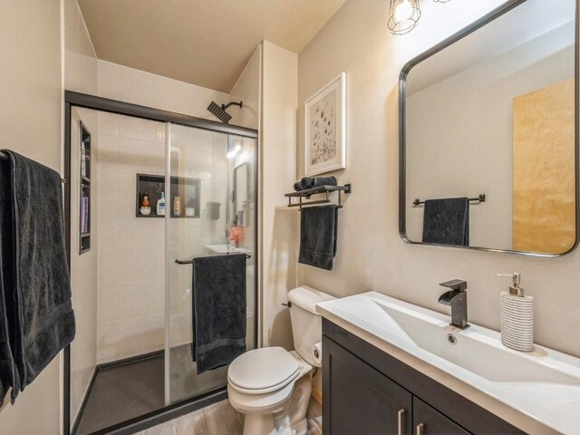 bathroom with vanity, a shower stall, and toilet
