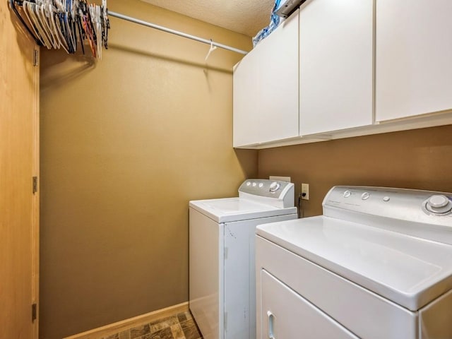 clothes washing area with washing machine and dryer, baseboards, and cabinet space