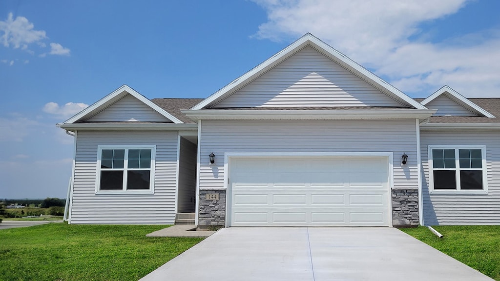 view of front of property featuring stone siding, an attached garage, a front yard, and concrete driveway