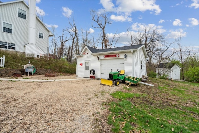 rear view of property featuring an outdoor structure and an attached garage