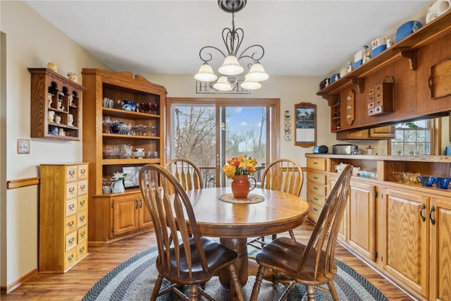 dining space featuring a chandelier, light wood-type flooring, a wealth of natural light, and baseboards