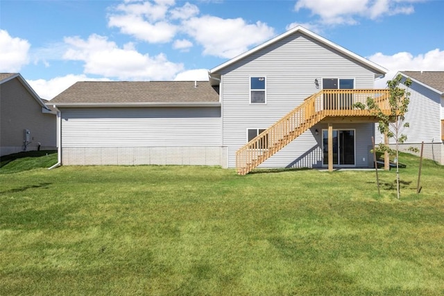 rear view of property with fence, a wooden deck, a lawn, and stairs