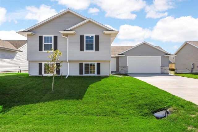 split level home with an attached garage, a front yard, and concrete driveway
