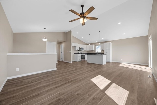unfurnished living room with vaulted ceiling, baseboards, and ceiling fan