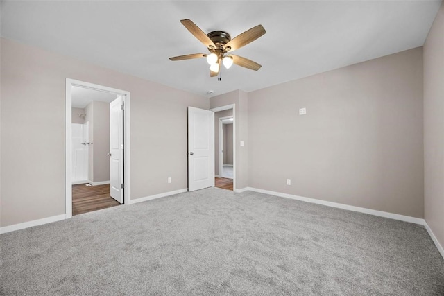 unfurnished bedroom with ensuite bath, carpet flooring, baseboards, and a ceiling fan