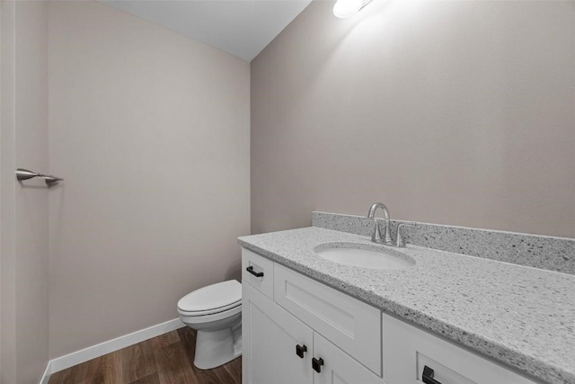 bathroom with baseboards, wood finished floors, vanity, and toilet