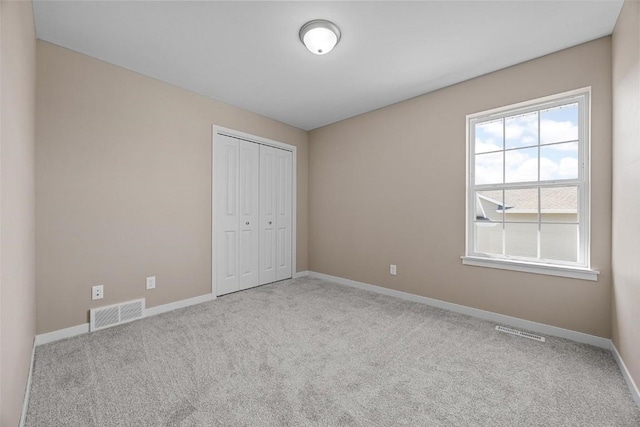unfurnished bedroom with baseboards, visible vents, and carpet