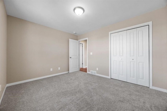 unfurnished bedroom with baseboards, carpet flooring, visible vents, and a closet