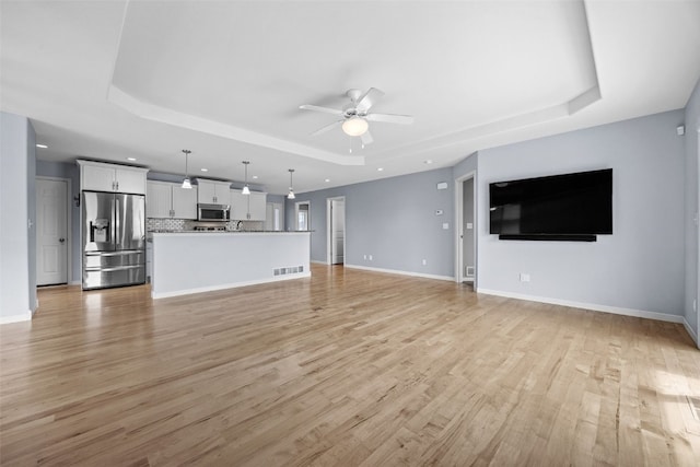 3211 35th Ave, Marion, IA 52302 - unfurnished living room with a raised ceiling, light wood finished floors, baseboards, and ceiling fan