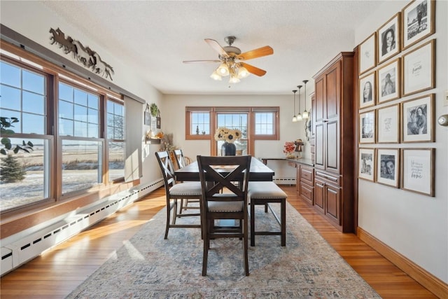 dining room with light wood finished floors, a textured ceiling, baseboards, ceiling fan, and a baseboard radiator