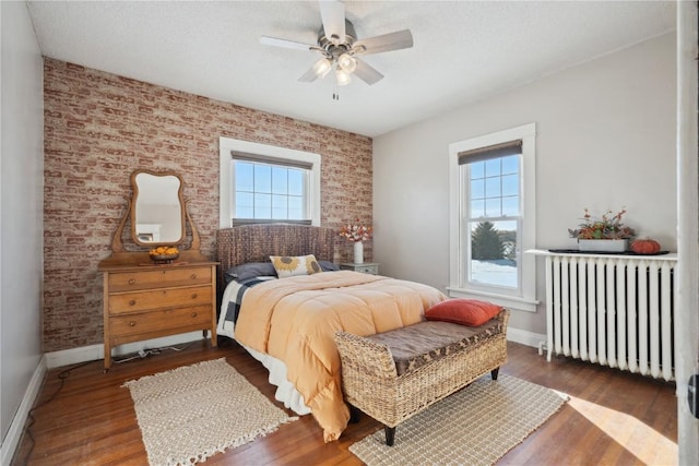 bedroom featuring multiple windows, baseboards, and radiator heating unit