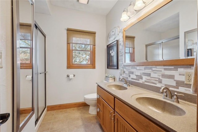 bathroom with backsplash, baseboards, a sink, and a stall shower