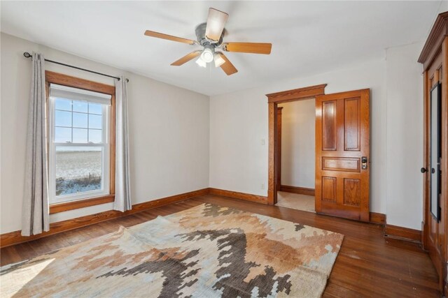 unfurnished bedroom featuring wood finished floors, baseboards, and ceiling fan
