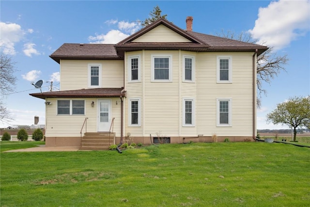 rear view of property featuring a yard and entry steps