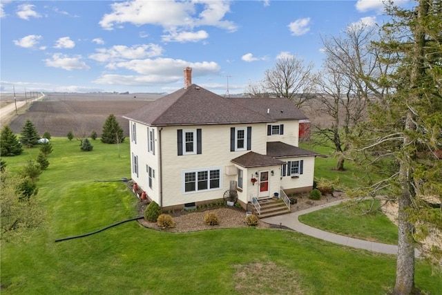 back of property with a shingled roof, a yard, and a chimney