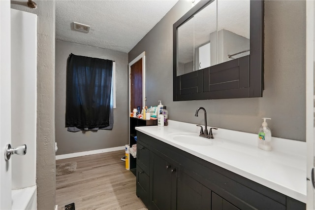 404 Main St, Shellsburg, IA 52332 - bathroom featuring vanity, visible vents, wood finished floors, baseboards, and a textured ceiling