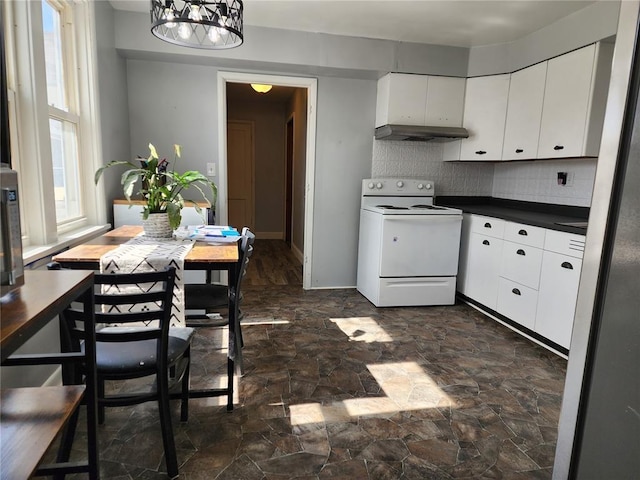kitchen with stone finish floor, white cabinetry, tasteful backsplash, white range with electric stovetop, and dark countertops
