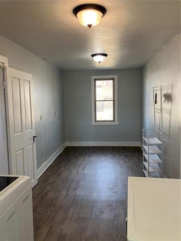 empty room with baseboards and dark wood-type flooring