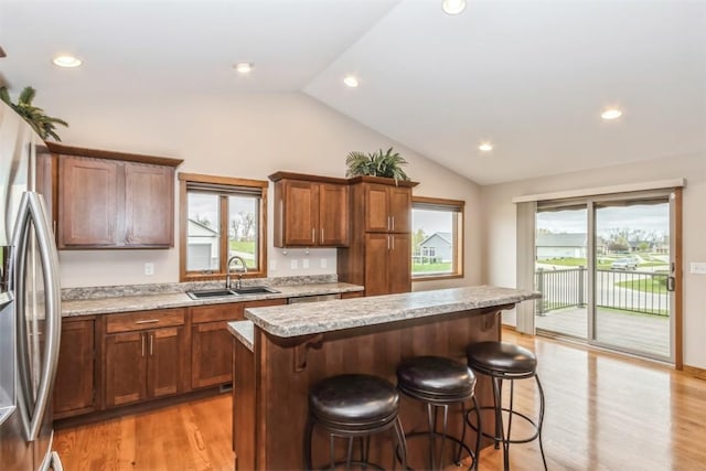kitchen featuring a breakfast bar, a sink, a wealth of natural light, and lofted ceiling