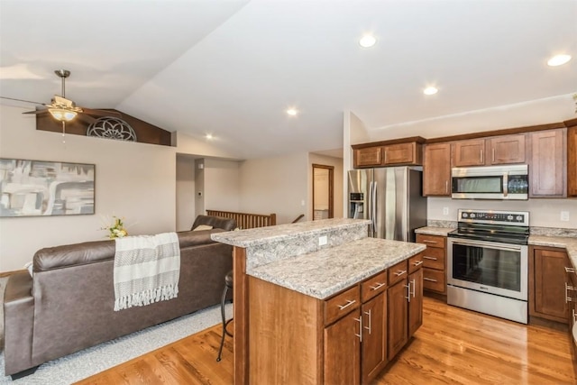 kitchen with light wood finished floors, appliances with stainless steel finishes, open floor plan, and a kitchen island