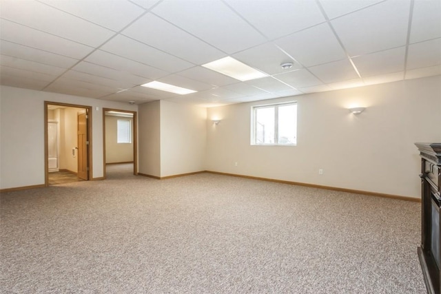 unfurnished living room featuring baseboards, light colored carpet, and a drop ceiling