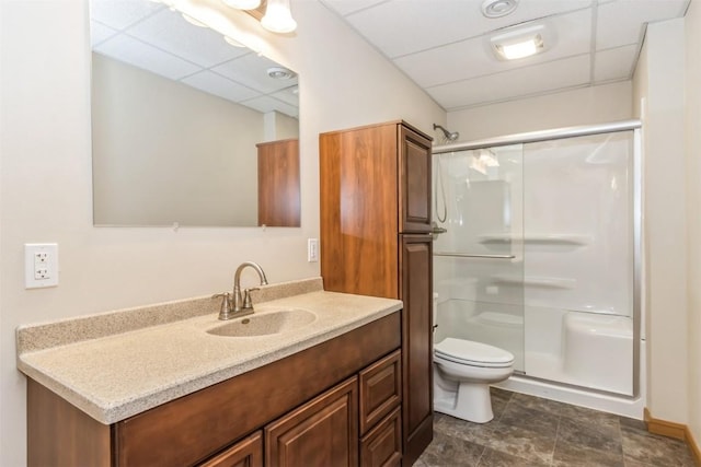 bathroom with a drop ceiling, toilet, and a stall shower