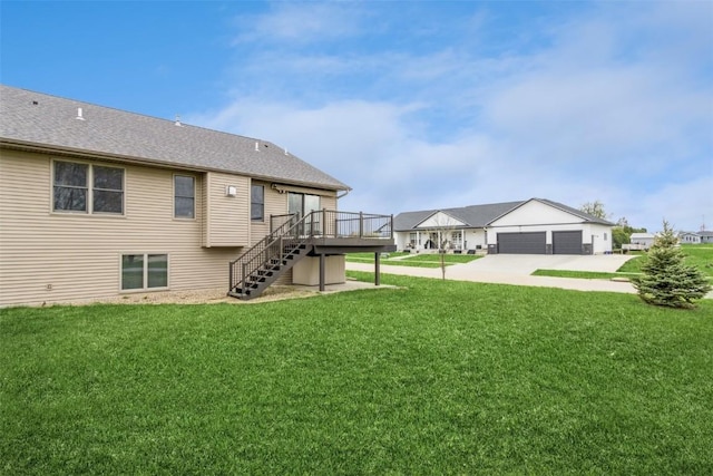 rear view of house featuring stairway, a lawn, driveway, roof with shingles, and a deck