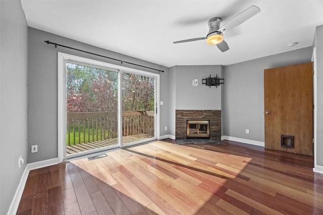 1156 Cambria Ct, Iowa City, IA 52246 - unfurnished living room with visible vents, baseboards, wood-type flooring, a ceiling fan, and a stone fireplace